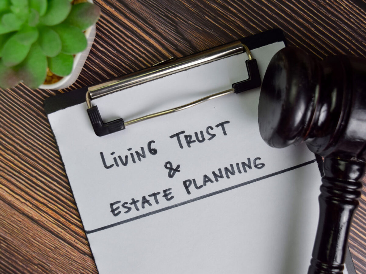Living Trust and Estate Planning written on a white clipboard with judges gravel.