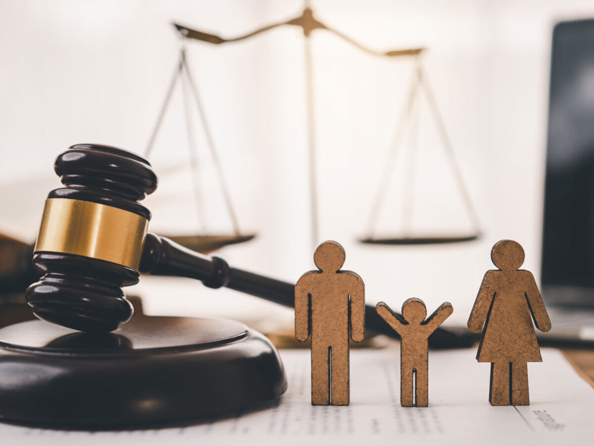 Wooden family with gavel and justice scales on a table for Family Law concept.